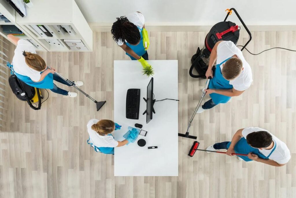 Office cleaning team disinfecting workspace with professional cleaning equipment.